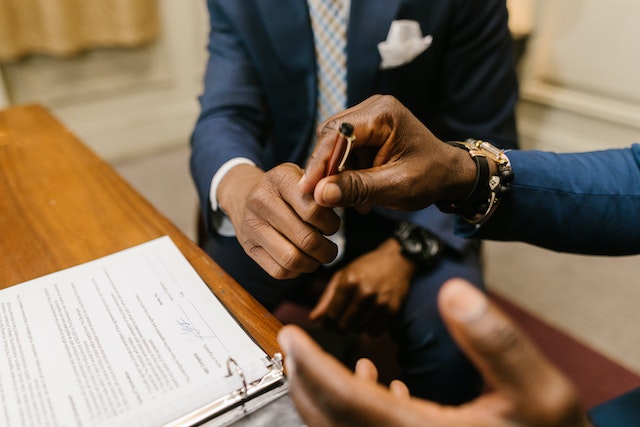 two people signing a document in a folder